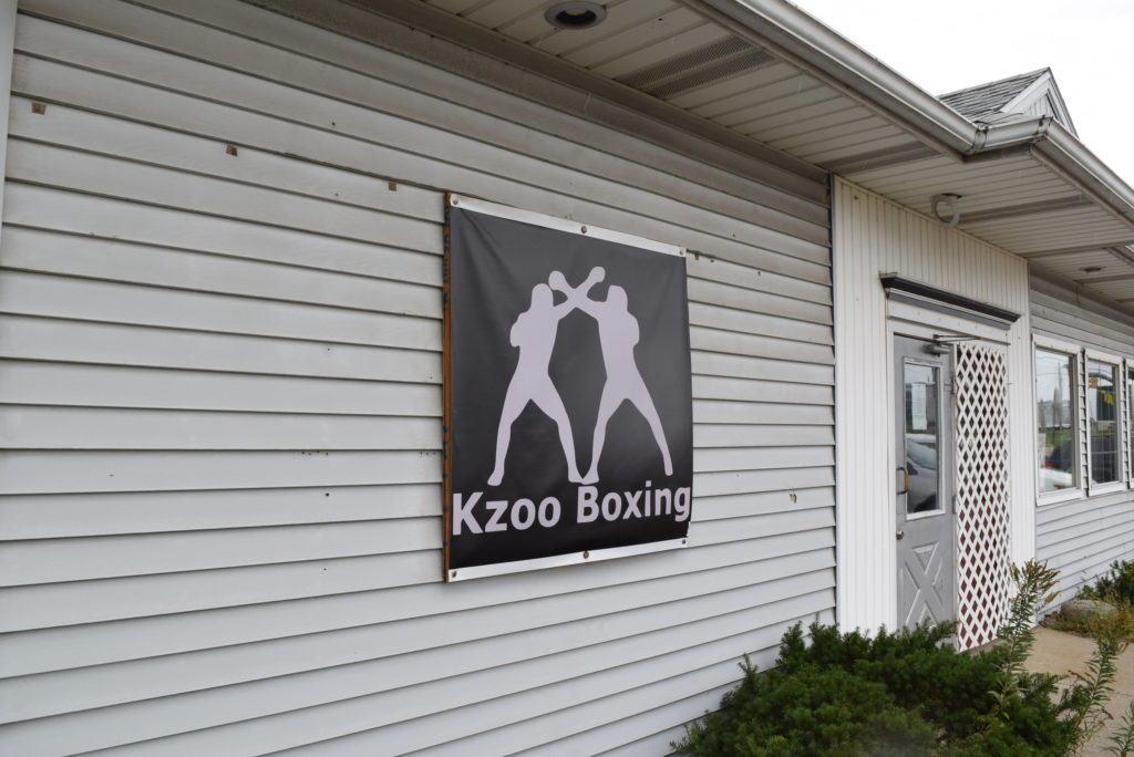 White building has sign with Kzoo boxing written on it. sign has two boxers